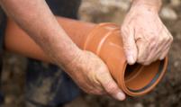 a plumber is holding a sewer pipe